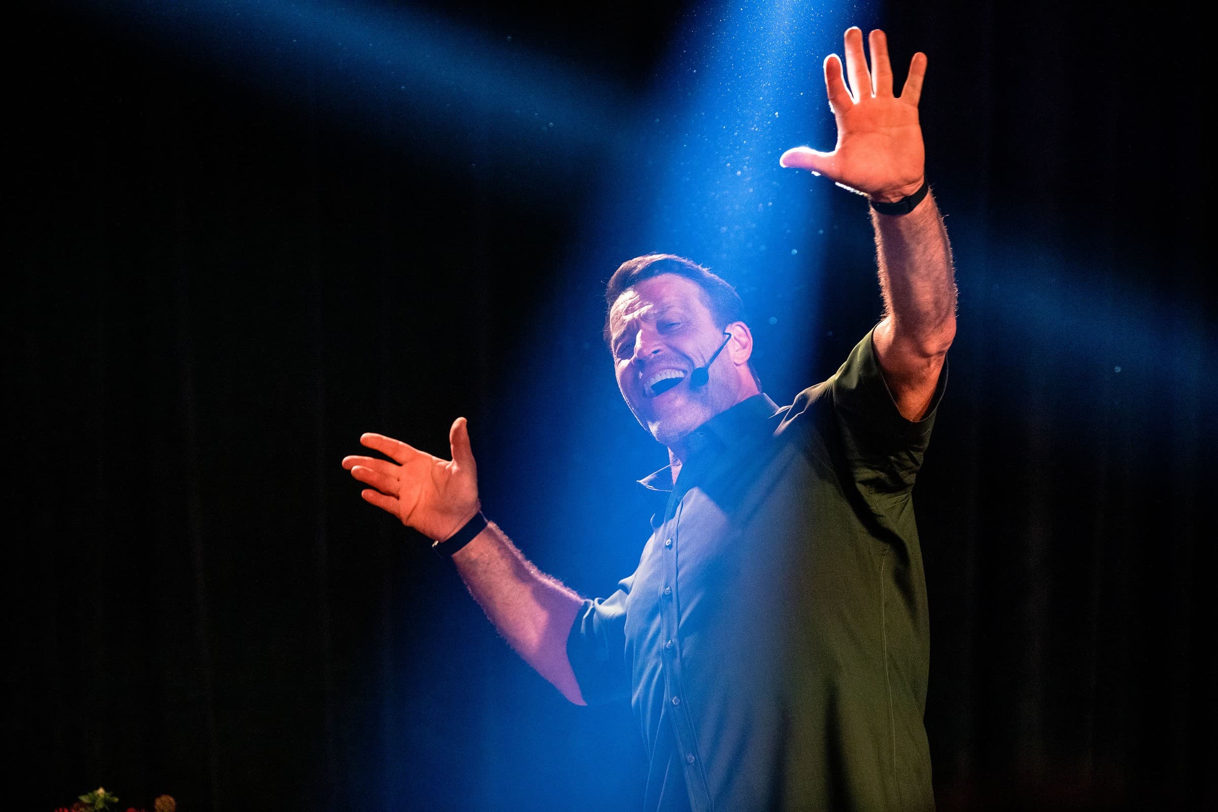 Tony Robbins on stage under a spotlight